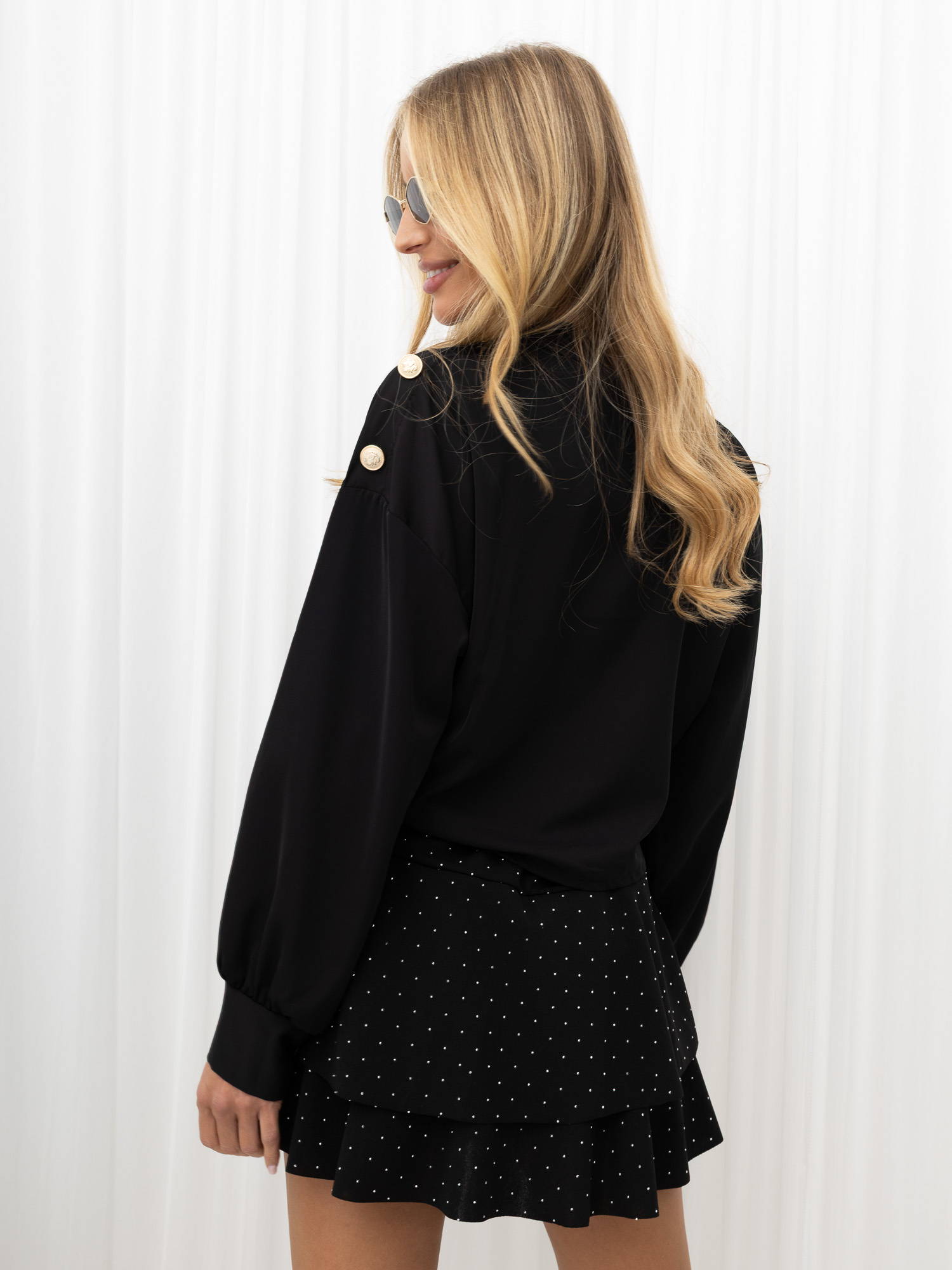 Schwarze Bluse mit Satin-Effekt und dekorativen Knöpfen.