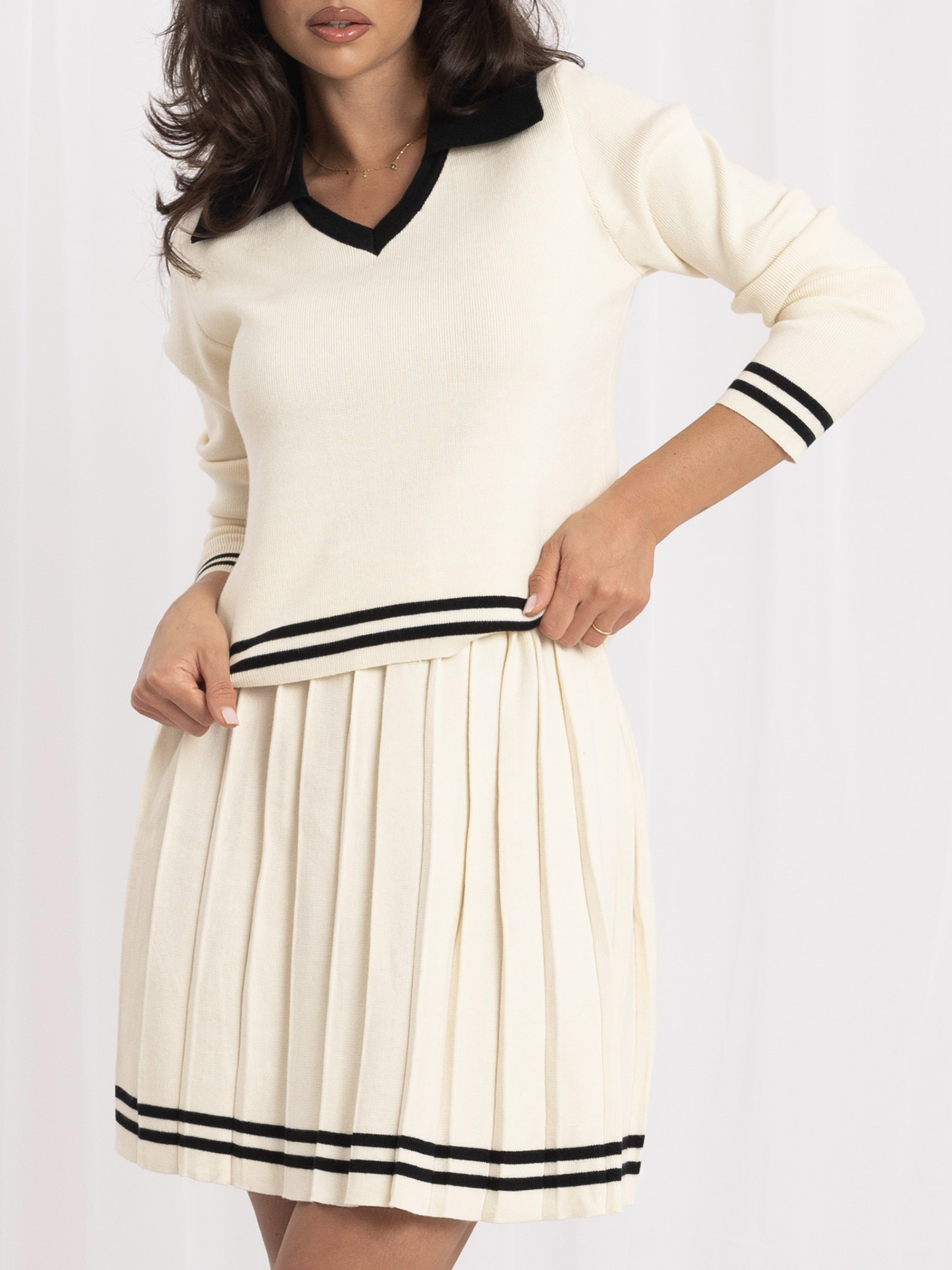 Helle beige Strickanzug mit plissiertem Minirock.