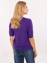 Lila Damenpullover mit einer Brosche in Form eines M.