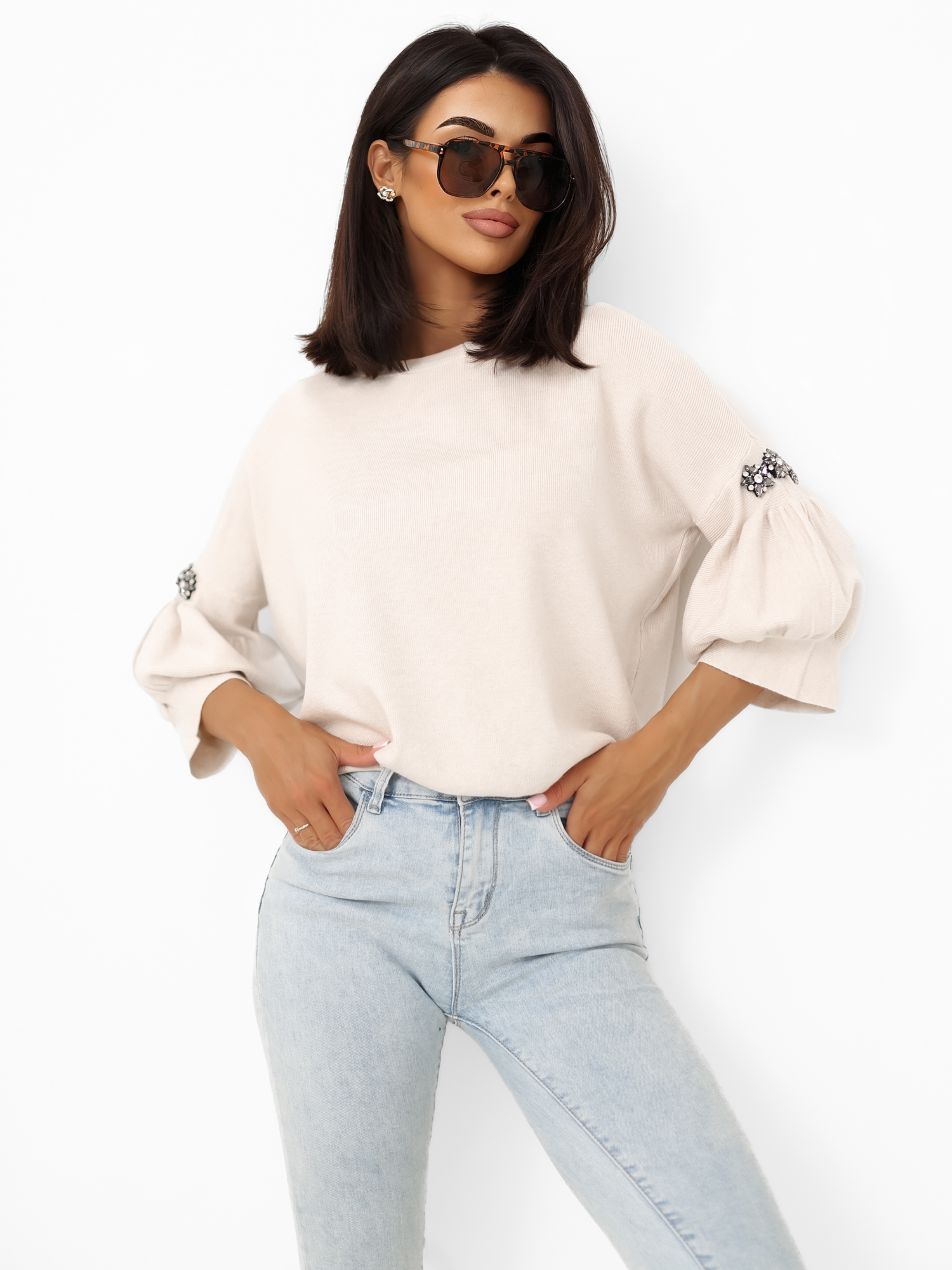 Helle beige Damenpullover mit Applikationen an den Ärmeln.