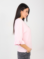 Helle rosa Pullover mit Rüschen an den Ärmeln.