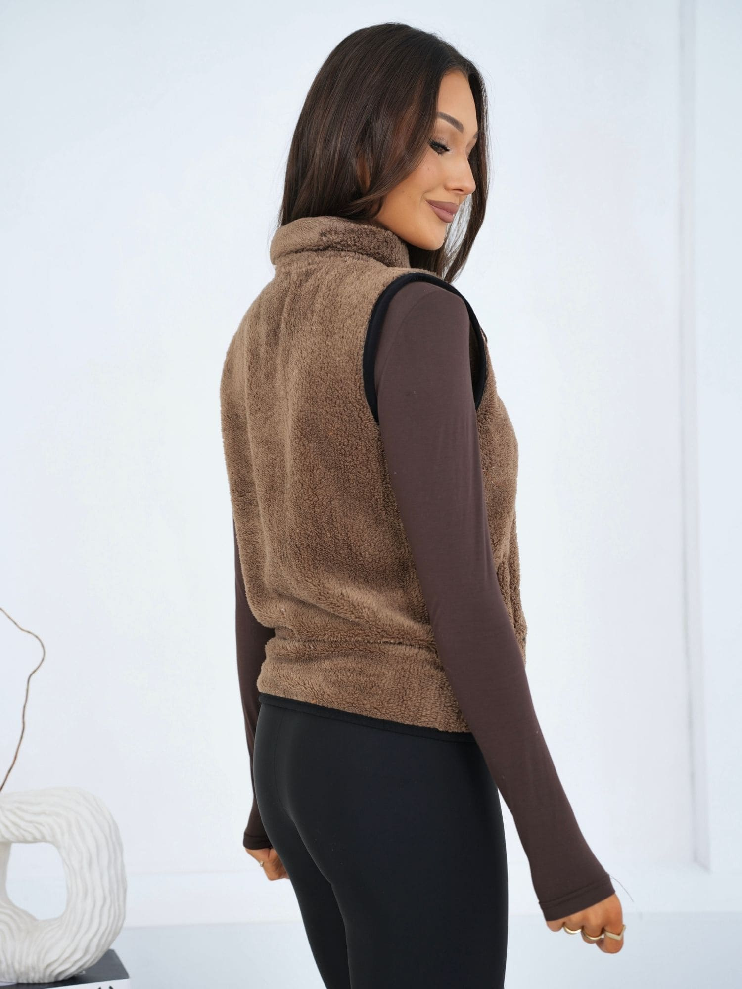 Tmavě béžová kožená vesta s límcem.