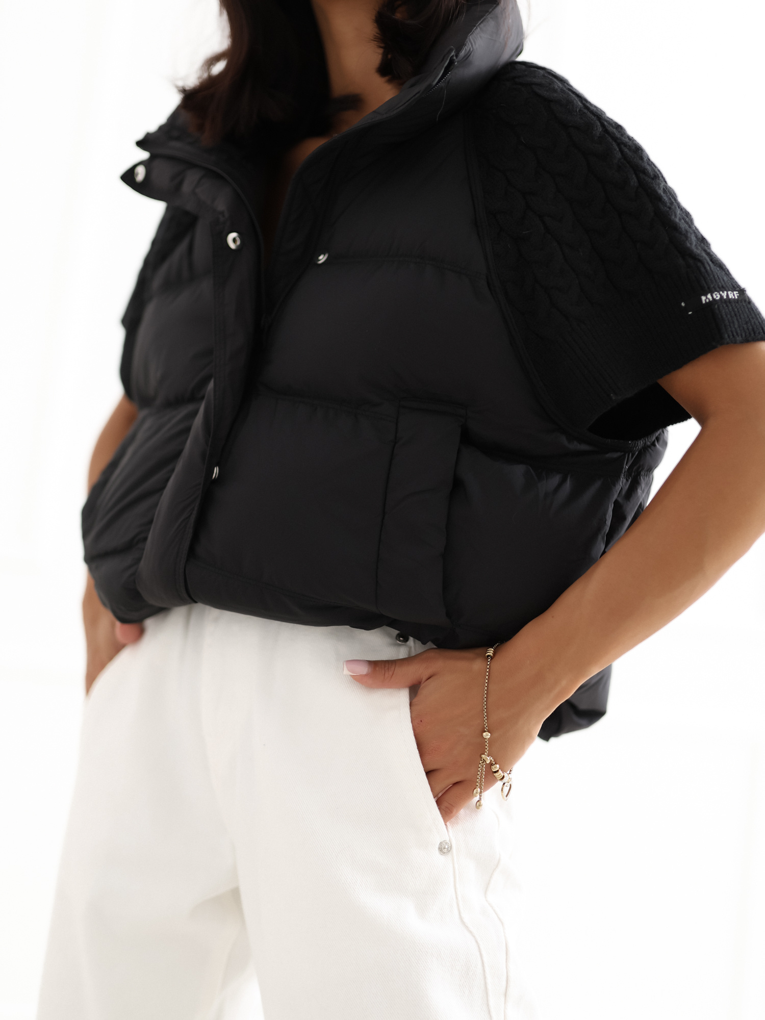 Black puffy vest with sweater sleeves.