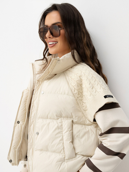 Šviesiai smėlinė pūkinė liemenė su mezginiais įsiuvais.