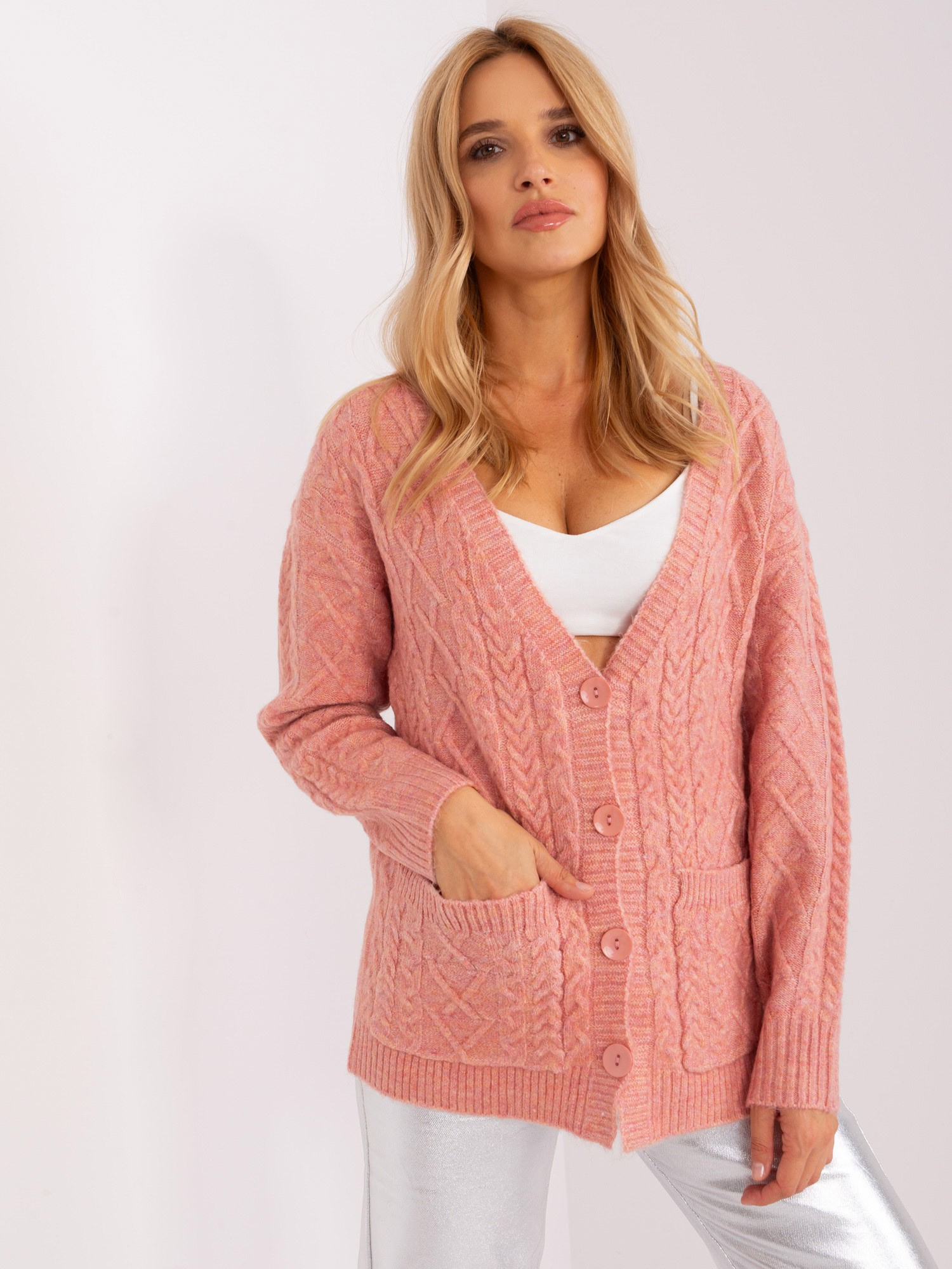 Jasnoróżowy sweter rozpinany w warkocze