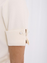 Ecru Pullover mit Schmuckknöpfen an den Manschetten.