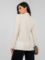 Jasnobeżowa damska marynarka zdobiona koronką