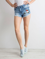 Blaue Jeansshorts mit Aufnähern.