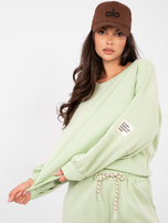 Pistazienfarbener Sweat-Anzug aus weichem Material.