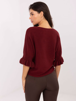 Burgundy sweater with ruffles at the sleeves.