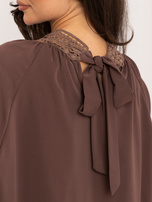Dunkelbeige Bluse mit Schleife auf dem Rücken.