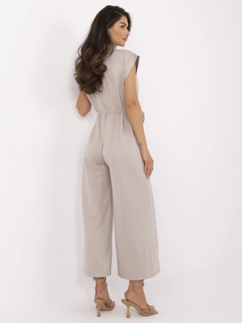 Beżowy damski kombinezon z kwiatową broszką