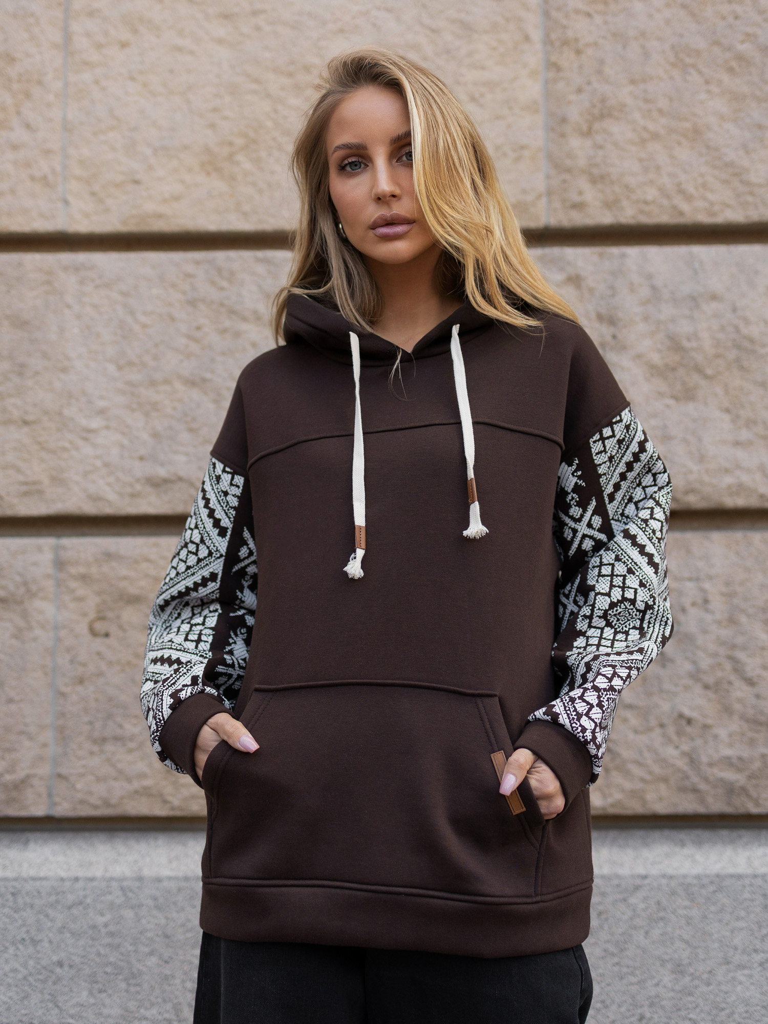 Schokoladenfarbener Kapuzenpullover mit dekorativen Ärmeln.