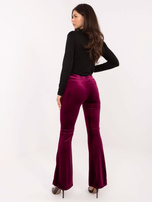 Burgundy velvet pants with a decorative belt.