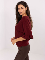 Burgundy sweater with ruffles at the sleeves.