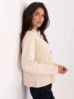 Helle beige Pullover mit dekorativen Elementen.