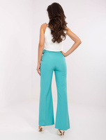 Hurt turquoise fabric pants with a belt.