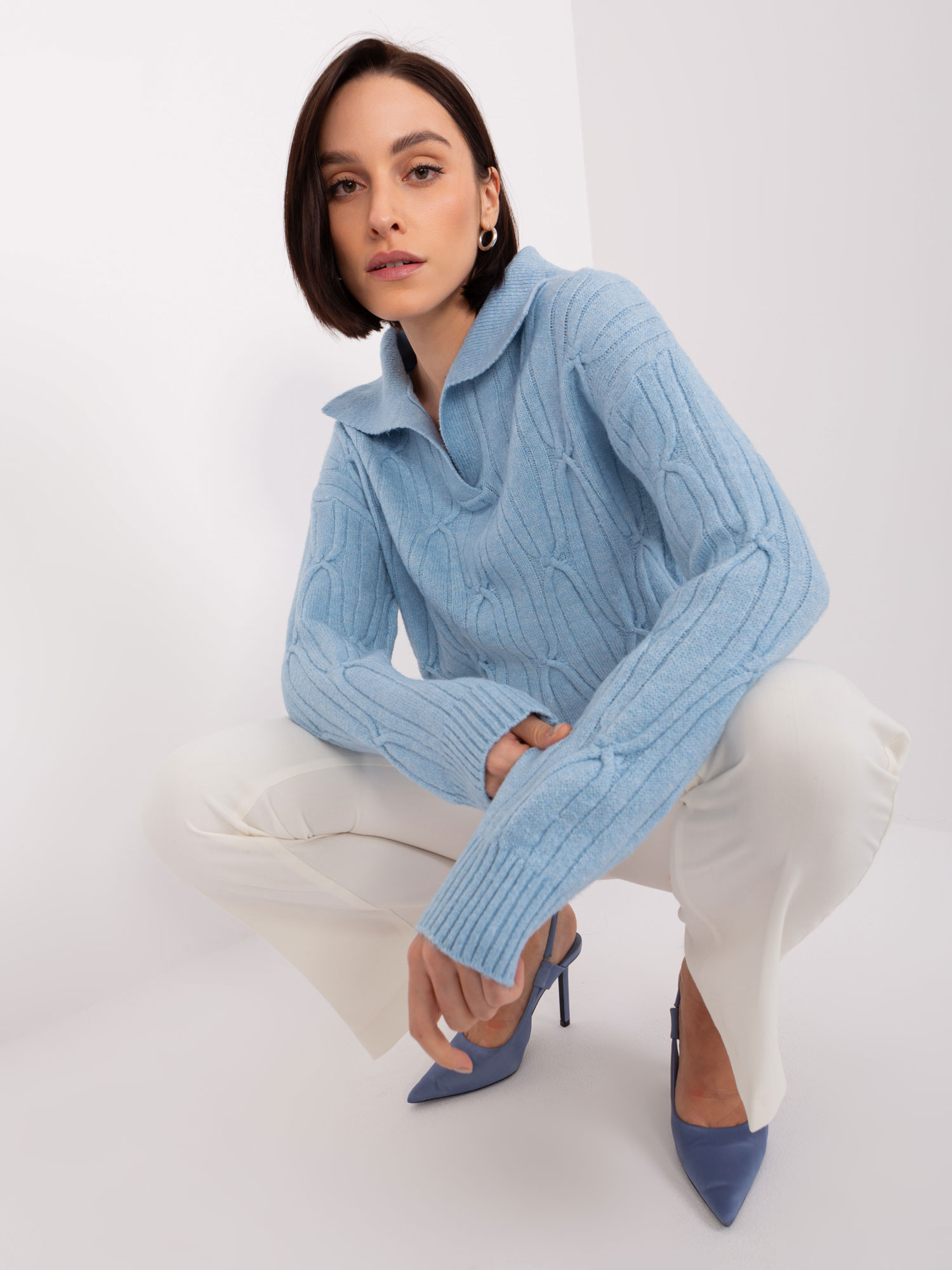 Šviesiai mėlynas megztinis su pynėmis ir apykakle.