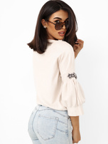 Helle beige Damenpullover mit Applikationen an den Ärmeln.
