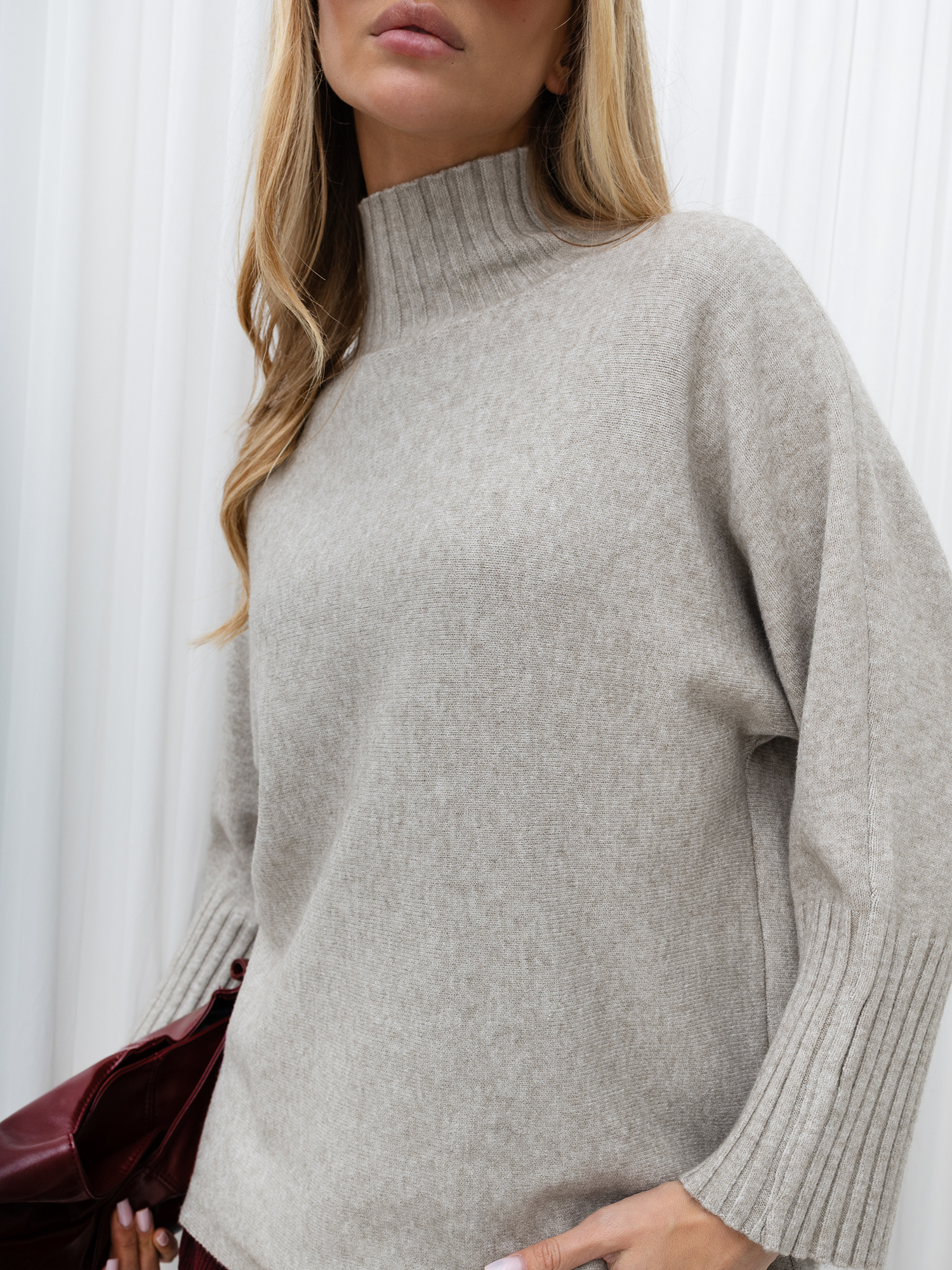 Beige women's turtleneck sweater with wide sleeves.