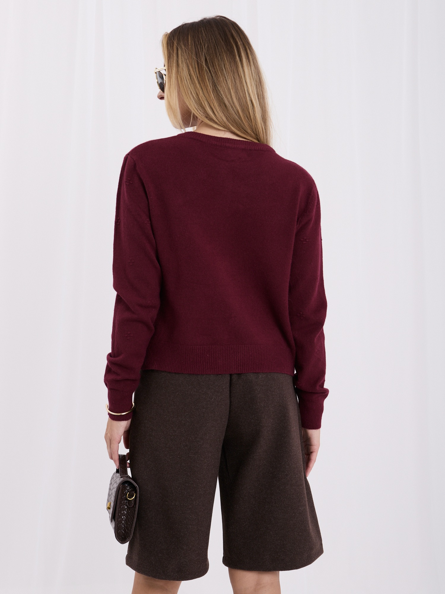 Burgundy women's cardigan with gold buttons.