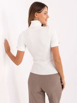 Ecrufarbener Pullover mit dekorativen Knöpfen an den Ärmeln.