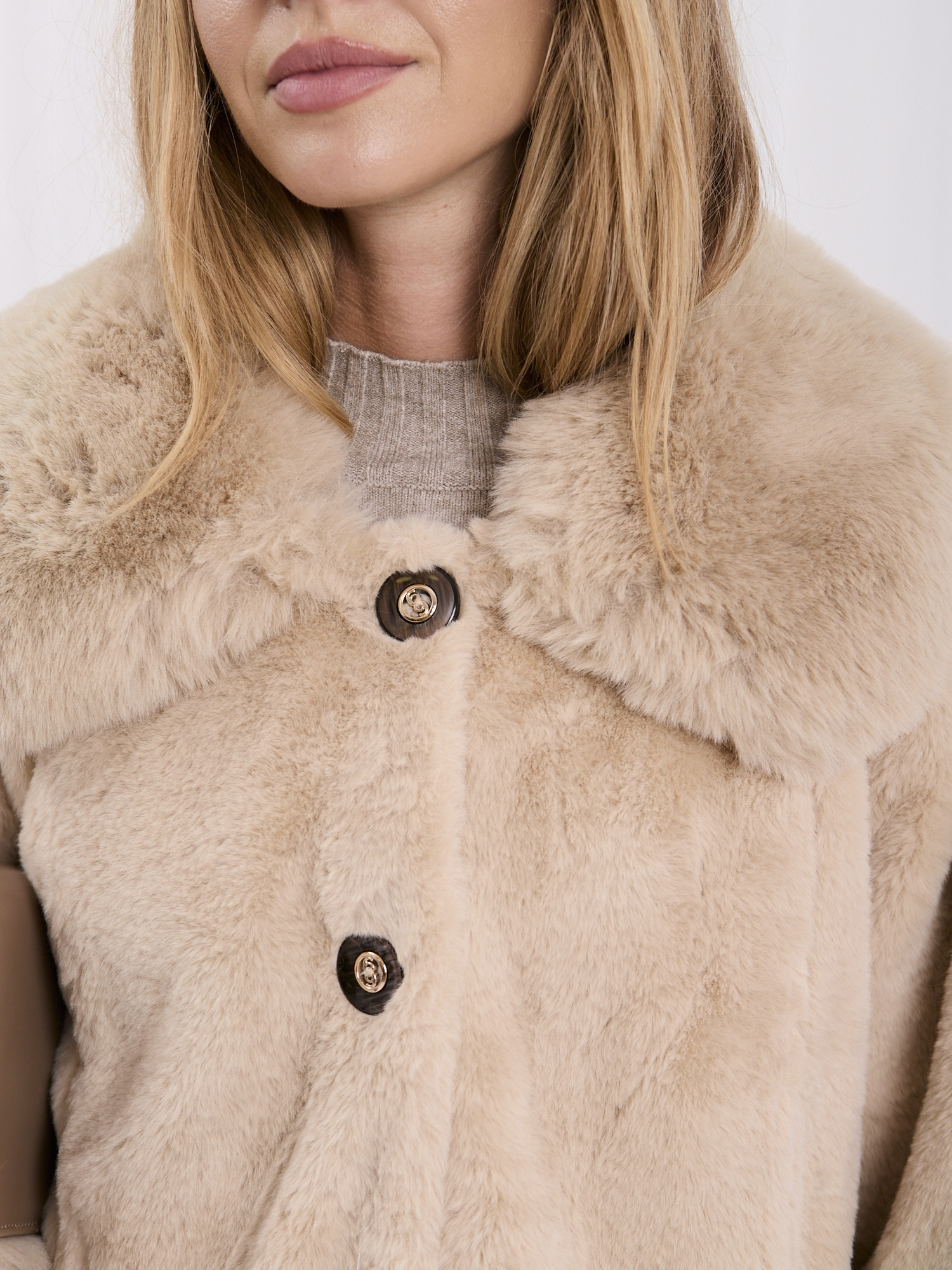 Light beige coat made of eco-fur with button closure.