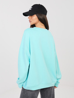 Mintfarbene Oversize-Bluse mit erhabenem Schriftzug.