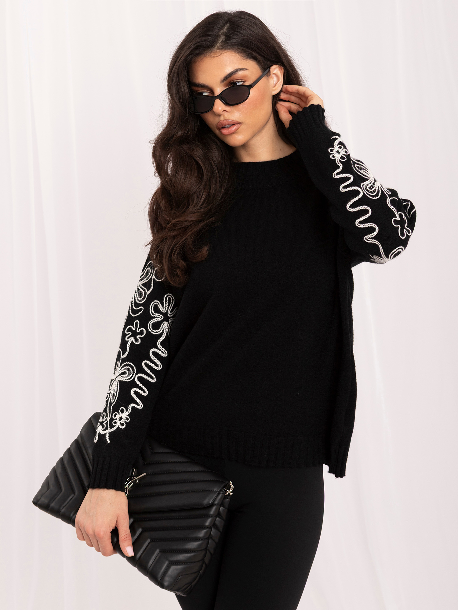 Schwarzer Damenpullover mit kontrastierender Stickerei.