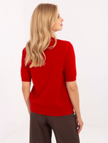 Roter Damenpullover mit einer Brosche in Form eines M.
