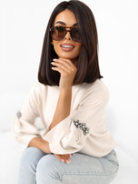 Helle beige Damenpullover mit Applikationen an den Ärmeln.