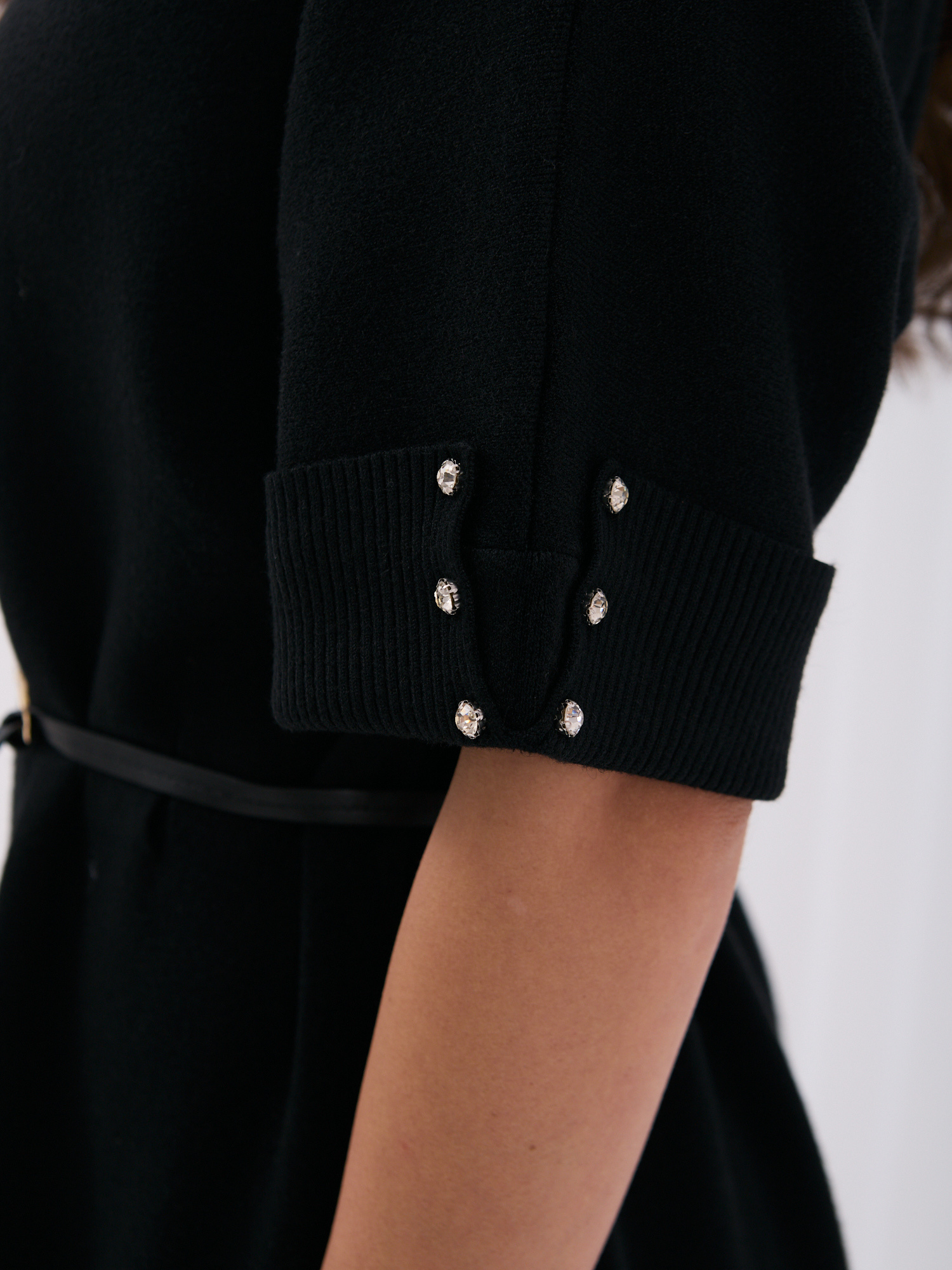 Schwarzes Strickkleid mit dekorativen Knöpfen an den Ärmeln.